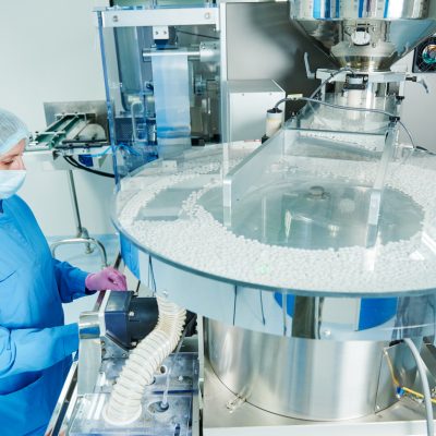 Pharmaceutics. Pharmaceutical industry worker operates tablet blister and cartoning packaging machine at factory