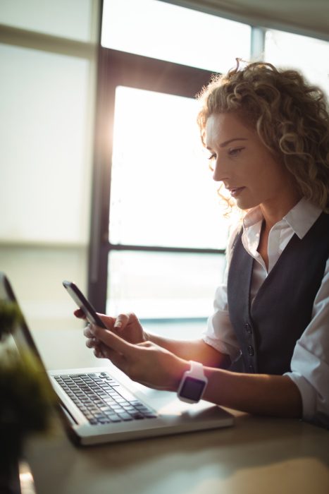 business-executive-using-mobile-phone-while-working-laptop_107420-65755