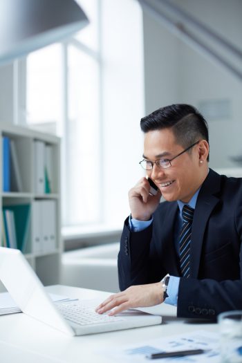 businessman-talking-typing-laptop_1098-3010