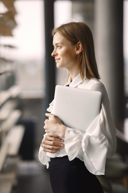 businesswoman-standing-office-with-laptop_1157-33421