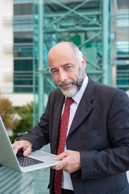 positive-confident-grey-haired-businessman-using-laptop_74855-3624