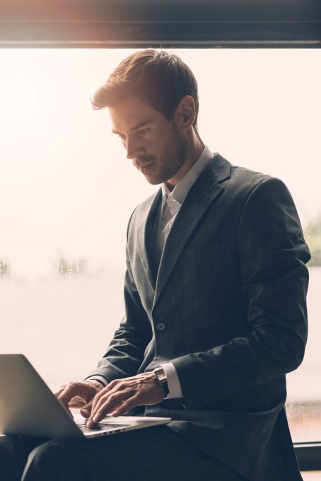 smart-young-businessman-typing-laptop_23-2147937535