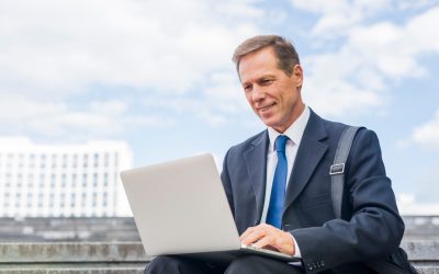 smiling-mature-businessman-using-laptop-outdoors_23-2147955325