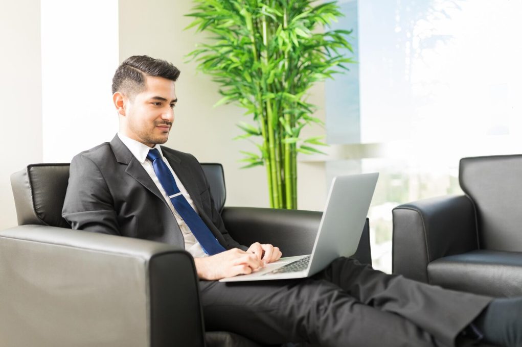 young-male-business-analyst-surfing-internet-laptop-computer-while-sitting-chair-lobby-office_662251-118